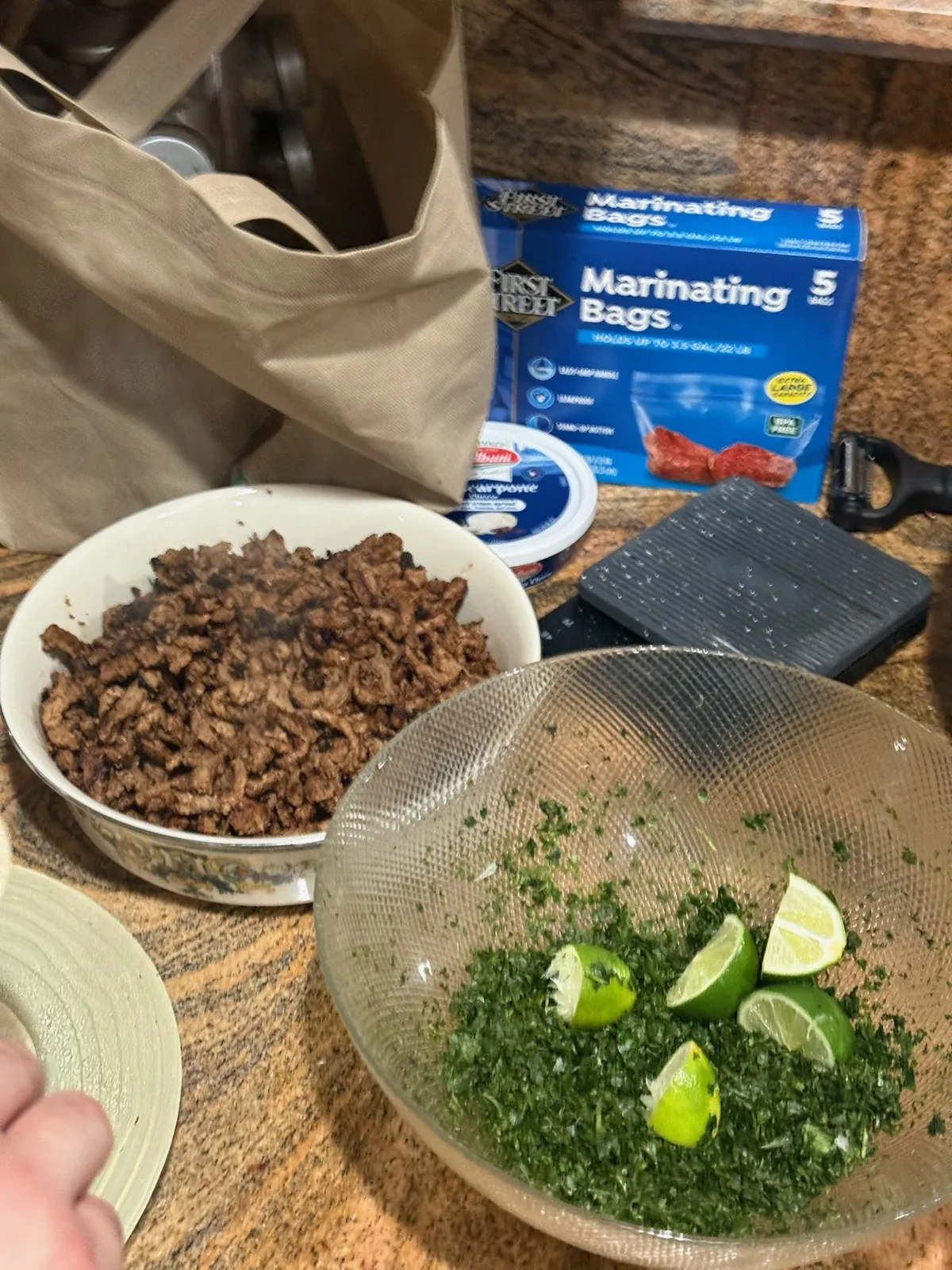 Cooked asada in a mixing bowl beside limes and chopped cilantro at the prep station