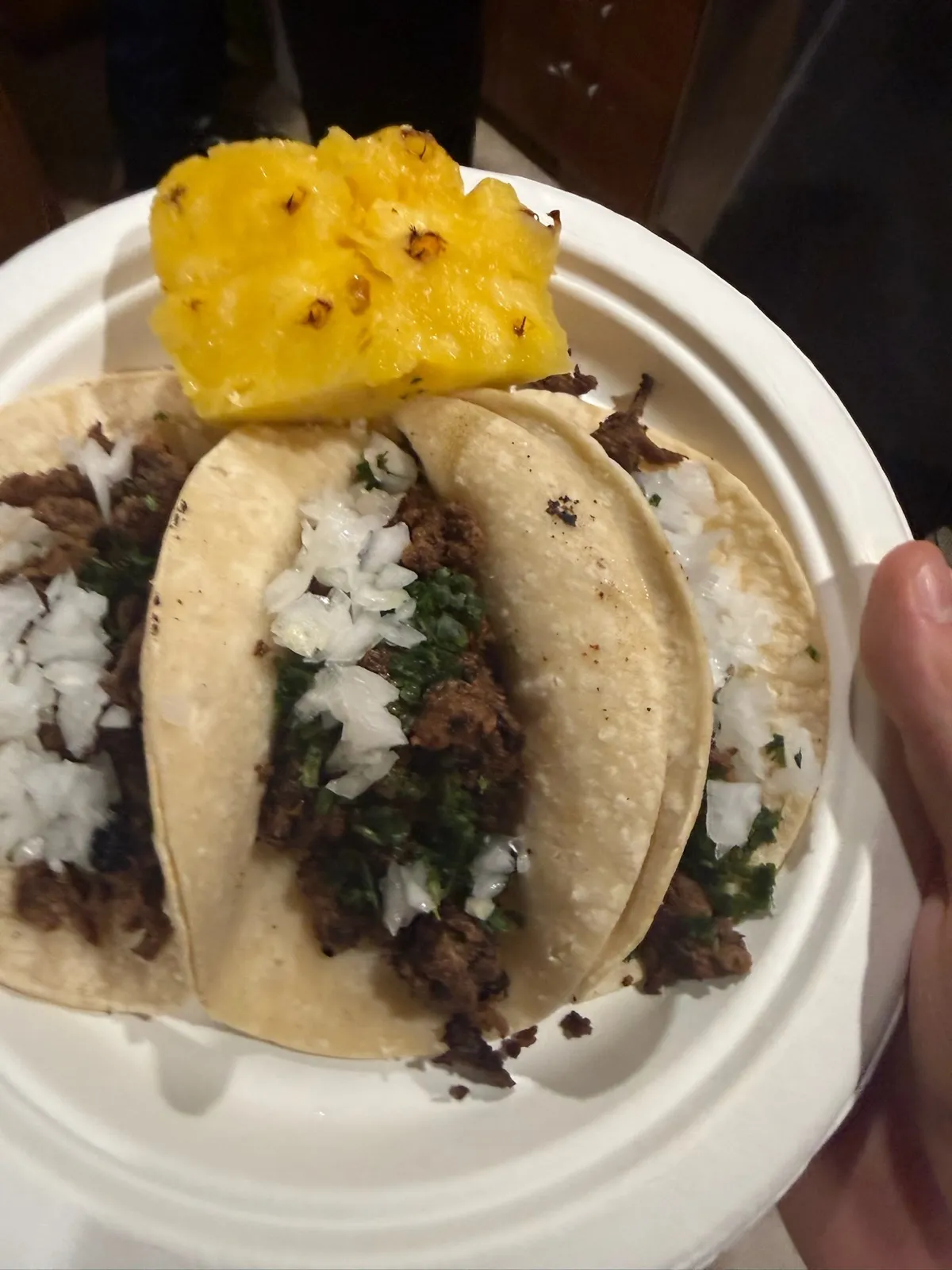 A finished asada taco plate topped with grilled pineapple, onion, and cilantro