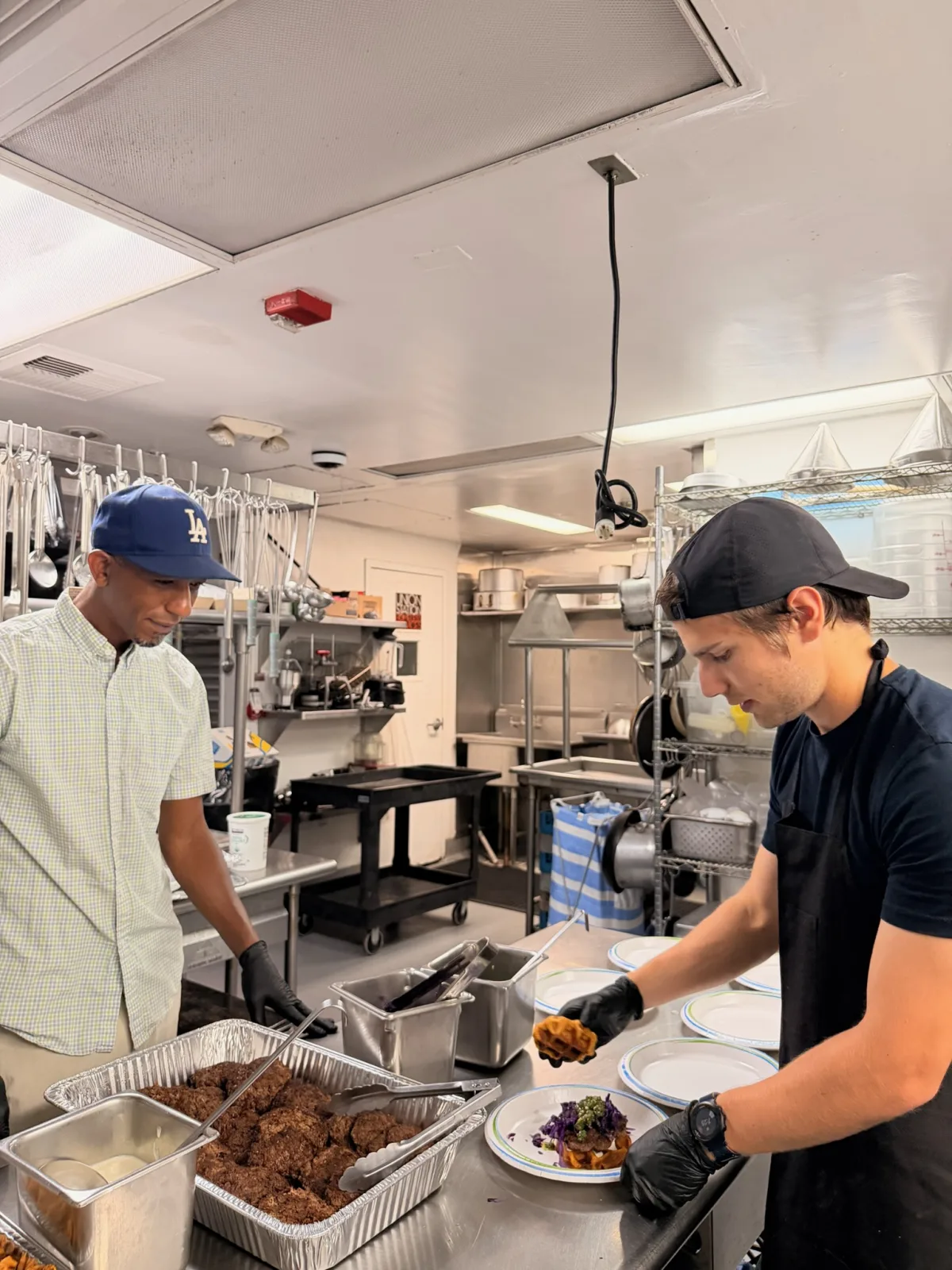 Volunteers plating sweet potato burgers and fries at the assembly line