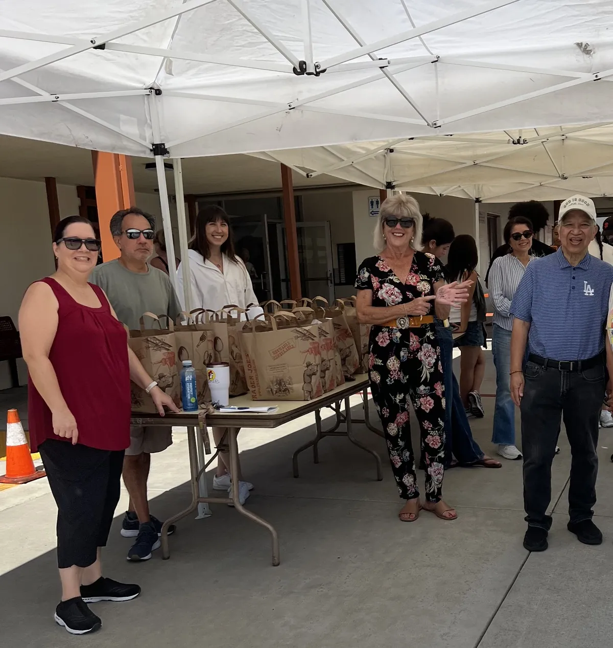 Volunteers standing beside a table of packed grocery bags at the Seed to Serve LA produce giveaway