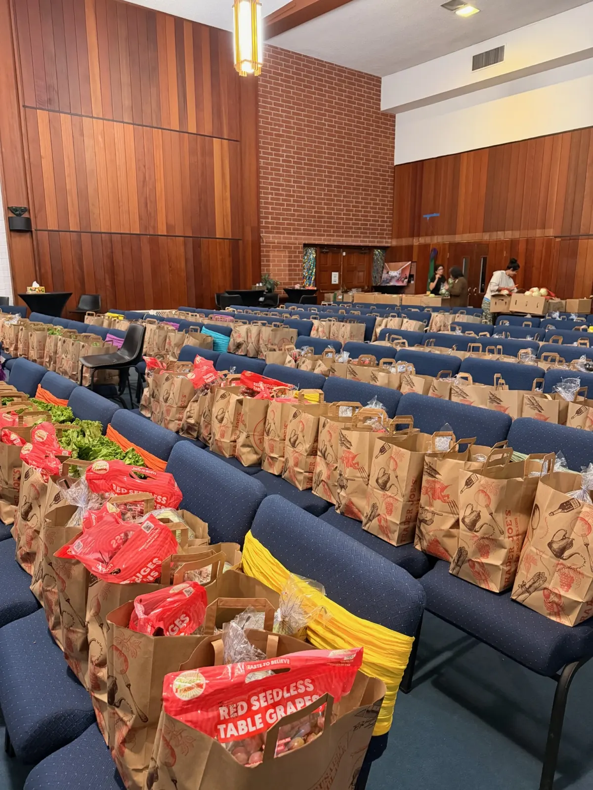 Rows of seats filled end to end with packed grocery bags of produce, grapes and greens on top, ready for the Saturday giveaway